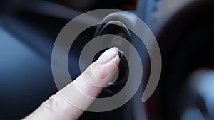 Female finger pressing start or stop engine button