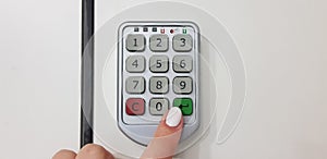 Female finger pushes green enter key on a door of security white locker photo