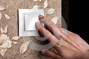 Female finger is turn on or off on light switch on wall