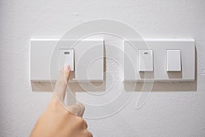 Female finger is turn on or off on light switch on white wall at home. Energy Saving, power, electrical and lifestyle concepts