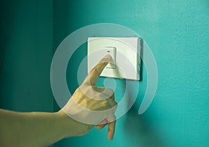 Female finger is turning on or off light switch