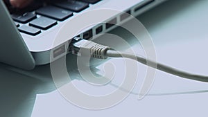 Female fingers plugging in ethernet cable into laptop port, network connection