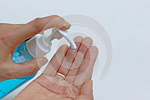 Female fingers pumping alcohol-based hand sanitizer gel on hand for killing germs, bacteria and virus.