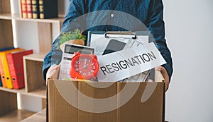 Female firm employee leaving the office with cardboard boxes containing office supplies and personal items after quitting to find