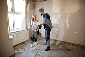 Female First Time Buyer Looking At House Survey With Realtor