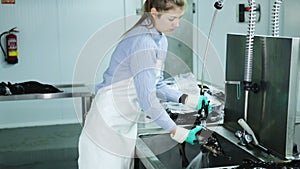 Female fish farm worker washing and packing freshly caught sturgeon