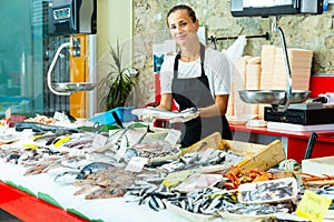 Female fishmonger offering fresh sea bass