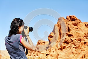 Female fit photographer takes pictures of rock formations.