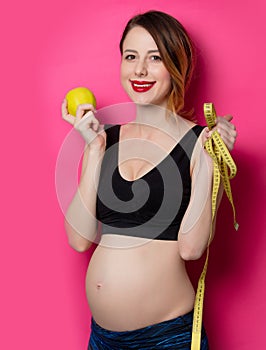 Female in fitness clothes with tape measure and apple