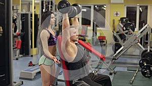 Female fitness instructor helping a young man at gym.