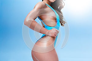 Female fitness model with a sporty body and long hair is posing in a light studio. Photo is made in a colourful and