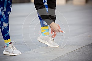 Female fitness runner tying sportshoe laces. Close-up hands and legs