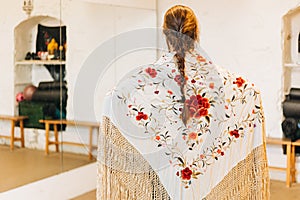 female flamenco dancer on her back wearing a shawl and braided hair on a dance studio