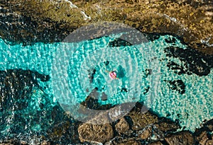 Female floating in a donut float ring toy in crystal clear  ocean