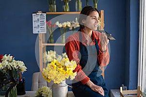 Female florist dictating voice message using artificial intelligence while working in her flower shop