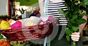 Female florist holding a bunch of pink rose and twine cord in flower shop