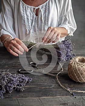 Female floristÃ¢â¬â¢s hands tied up bunch of lavender by twine. Working table photo