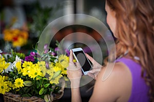 Female florist taking photogrpah of flower basket