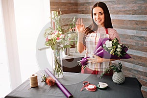 Female florist at work: pretty young dark-haired woman making fashion modern bouquet of different flowers. Women working