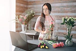 Female florist at work: pretty young dark-haired woman making fashion modern bouquet of different flowers. Women working