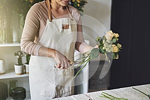 Female florist working in her flower shop trimming a bouquet