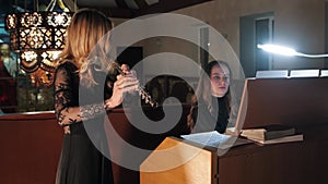 Female flutist and organist playing music in church
