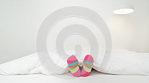 Female foot in warm stripe wool sock ,Woman sleeping and relaxing in bed concept. Warm and cozy white socks in the bed