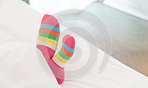 Female foot in warm stripe wool sock ,Woman sleeping and relaxing in bed concept. Warm and cozy white socks in the bed