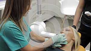 A female Footage of a dentist making an x-ray of a patients teethin hijab suggesting her patient which tooth color to take