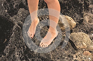 Female foots with painted nails on rocks close-up