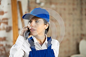 Female foreman talking on phone in building under construction