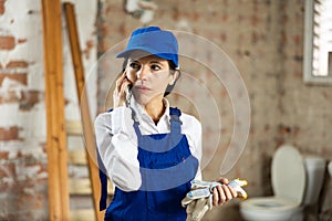 Female foreman talking on phone in building under construction