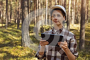 female forester or forest engineer working in the woods with digital tablet. forestry, forest management and development