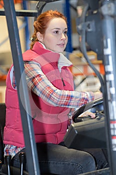 Female fork lift truck driver in factory