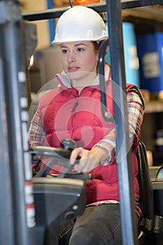 Female fork lift truck driver in factory