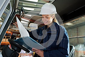Female fork lift truck driver looking at clipboard