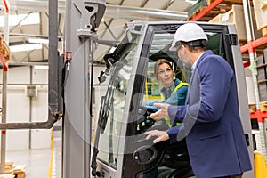 Female forklift driver talking with manager in warehouse, order picking. Warehouse worker preparing products for