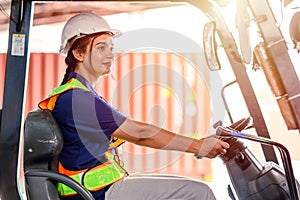 Female forklift operator working in a warehouse. Portrait of young Indian woman driver sitting in forklift and smiling working in