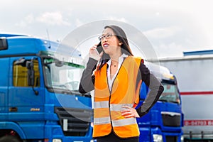 Female forwarder in front of trucks on a depot