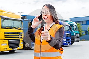 Female forwarder in front of trucks on a depot