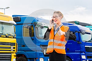 Female forwarder in front of trucks on a depot