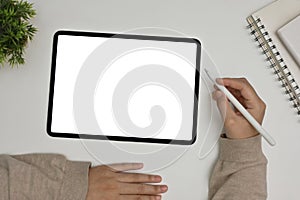 A female freelancer using digital tablet. Workspace with tablet mockup on white tabletop. top view