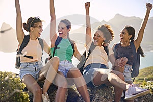 Female Friends With Backpacks On Vacation Taking A Break On Hike In Countryside With Arms In The Air