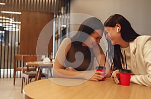 Female friends drink coffee or tea from red cups with straws