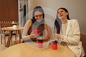 Female friends drink coffee or tea from red cups with straws
