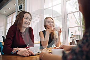 Female friends drinking coffee having a pleasant conversation in a cozy romantic restaurant