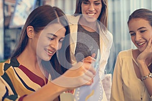 Female friends giving birthday gift. Girl opens her present.