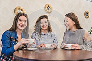 Female friends having a coffee together. Three women at cafe drinking, talking, laughing and enjoying their time