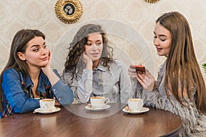 Female friends having a coffee together. Three women at cafe drinking, talking, laughing and enjoying their time