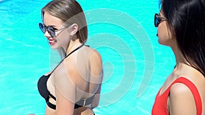 Female friends preparing to swim in pool, summer vacation in luxury resort